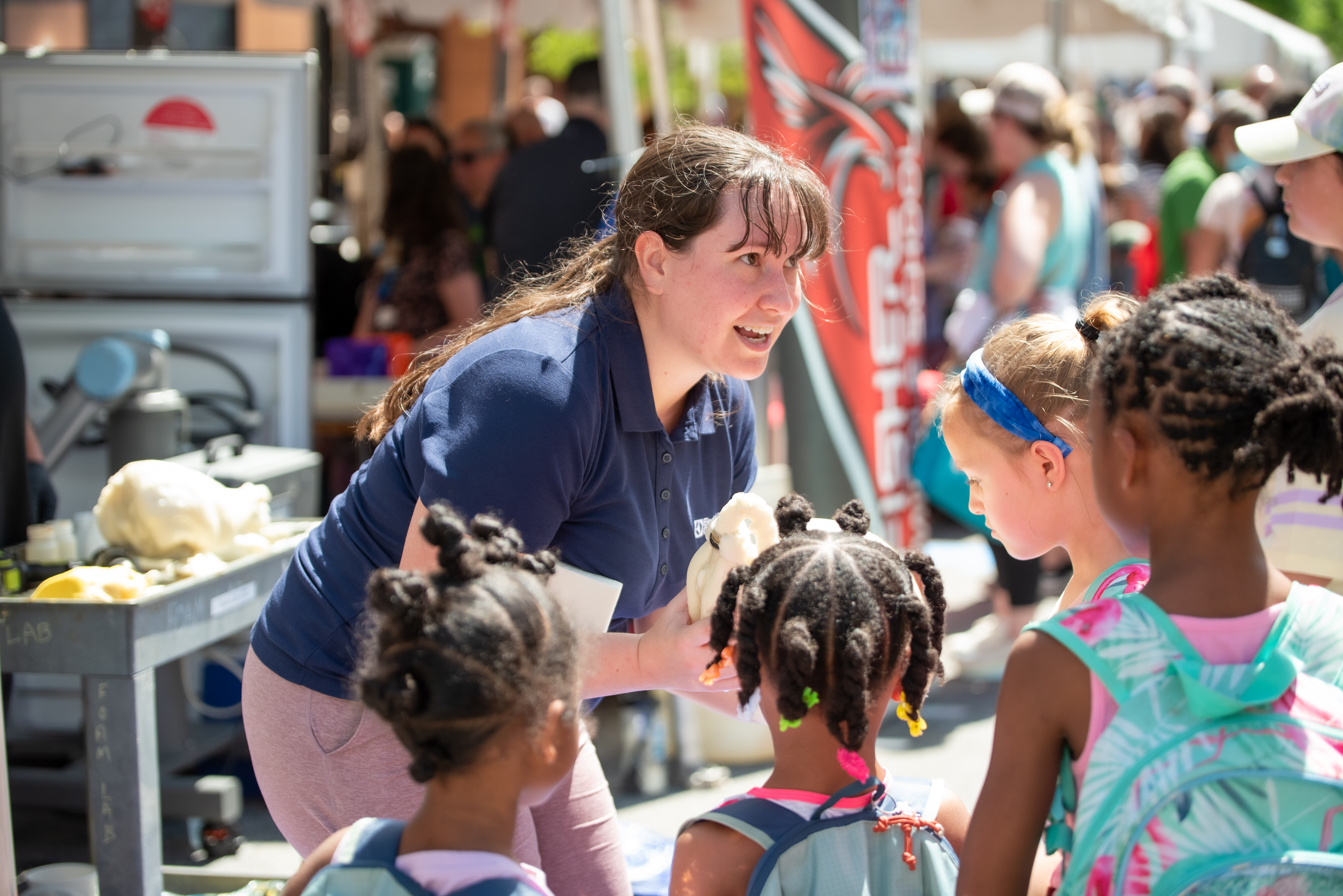 A woman speaking to children participating at a festival booth  (opens link in new window)